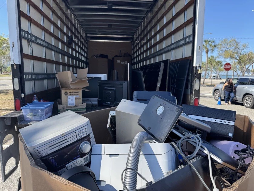 Photo of the back of a moving truck full of E-Waste and other recyclables